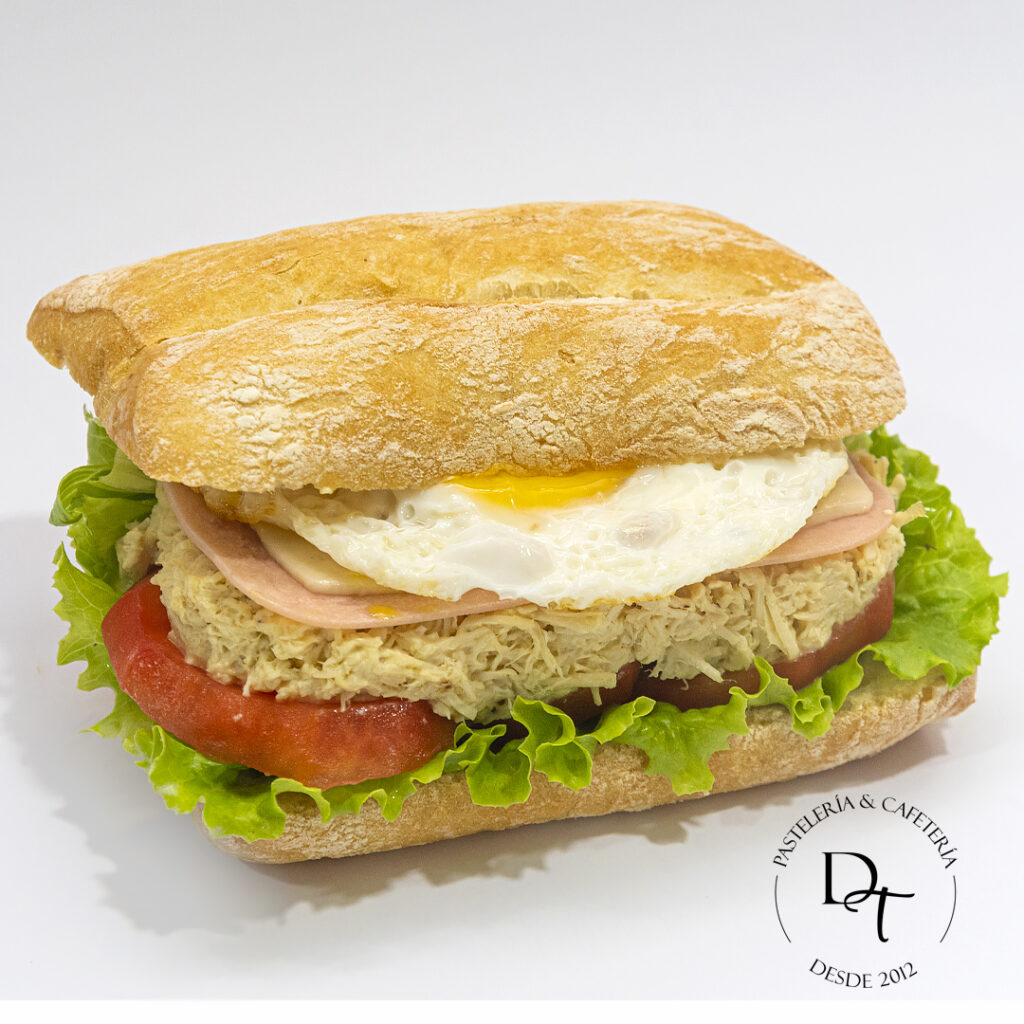 Pan ciabatta, pechuga de pollo picada, lechuga, tomate, huevo frito, queso, jamón inglés a la mayonesa, salsas a elección.