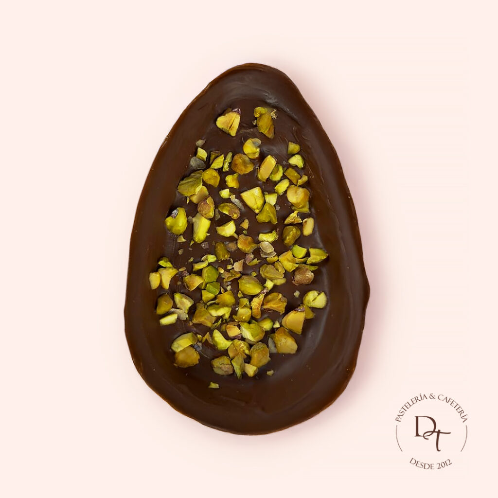 Huevito de Pistacho Bombón de chocolate en forma de medio huevo, relleno de crema de pistacho y pistacho crocante.